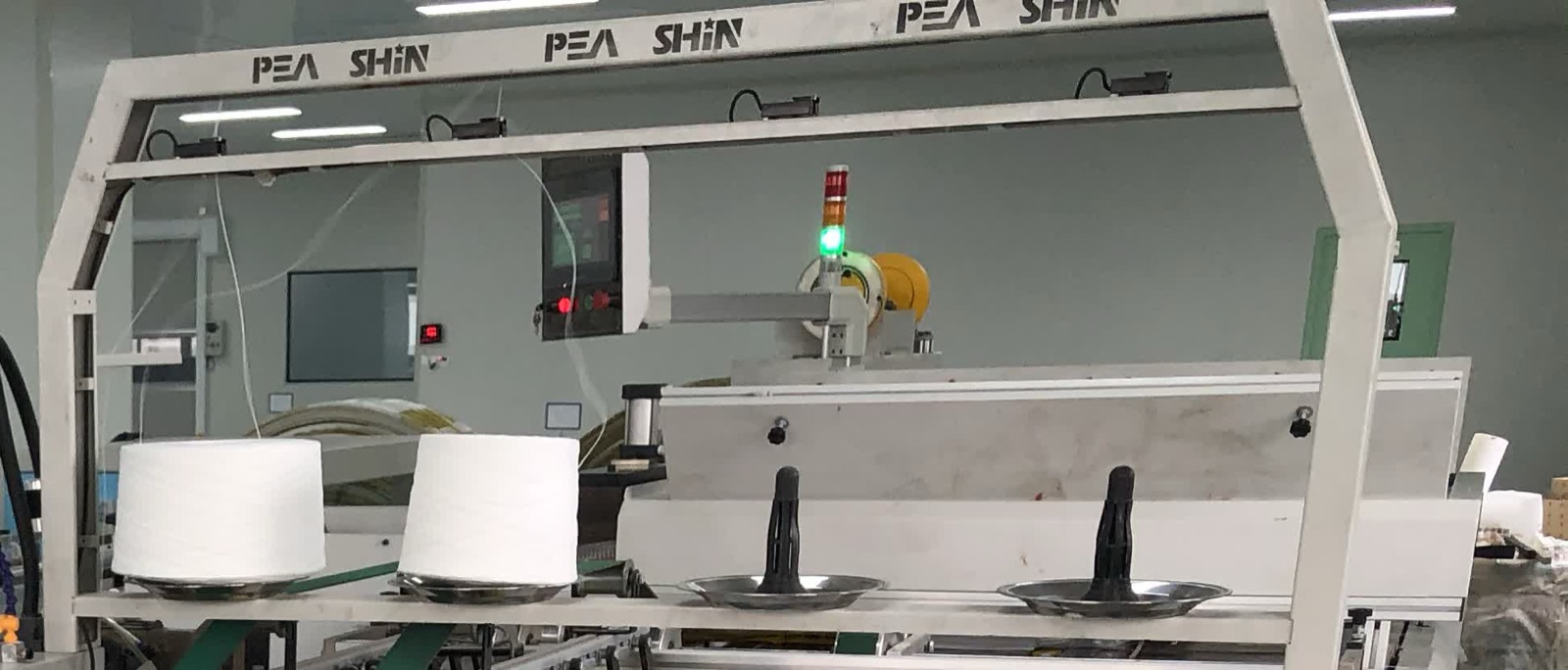 Bag-making gantry with sewing thread cones and lit green status light