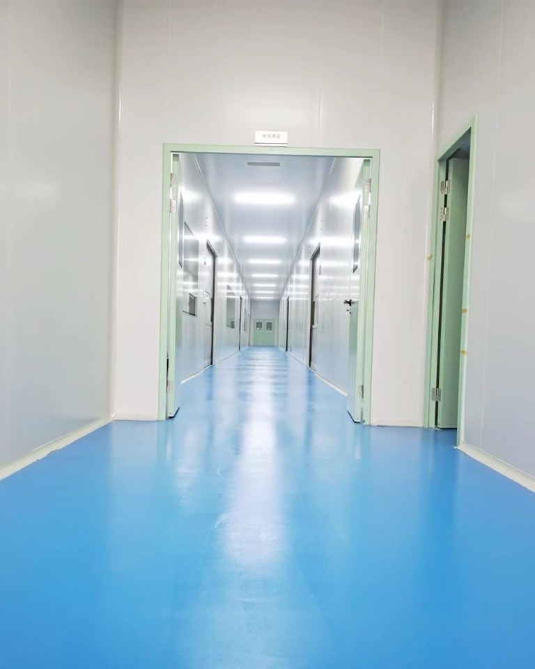 Long cleanroom corridor with sealed doors and coved blue floor