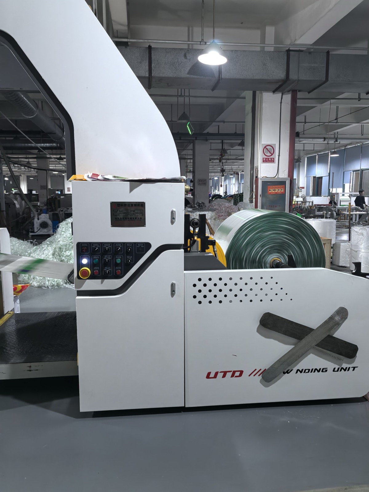 Green-striped woven roll winding onto an extrusion laminating unit