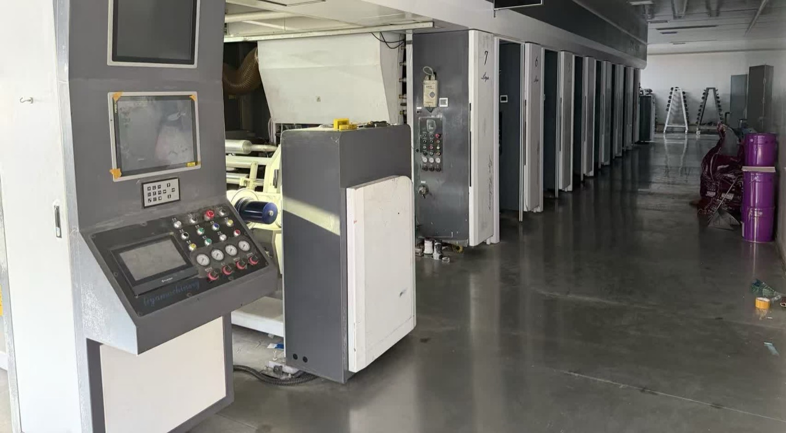 Multi-station printing press receding down a polished factory aisle