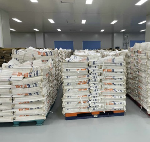 Finished woven sacks bundled and stacked on pallets in a lit warehouse bay
