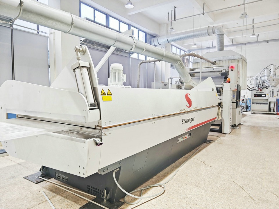 Starlinger tape extrusion line on a plant floor with tape running out of the machine and a second Starlinger unit behind