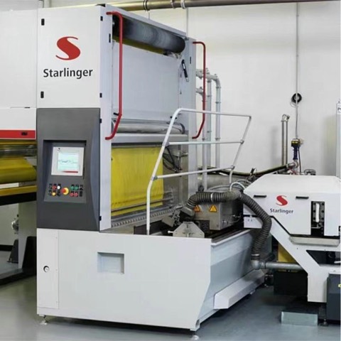 Starlinger line with a yellow film web threaded through it and a touchscreen control station