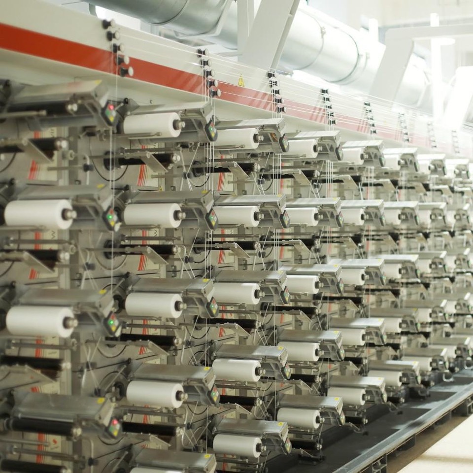 Bank of automatic tape winders in rows, each holding a bobbin of spun tape