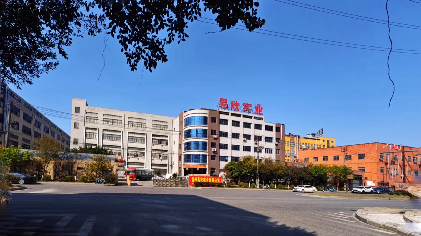 Factory exterior with rooftop company lettering and a banner over the gate
