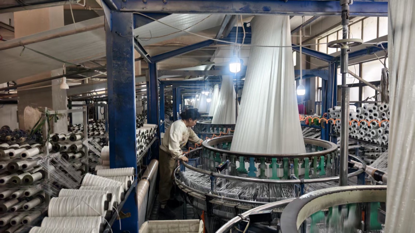 Circular weaving hall with tubular fabric cones and creel racks